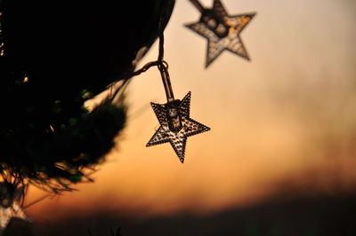 Low angle view of christmas decorations hanging against sky at sunset