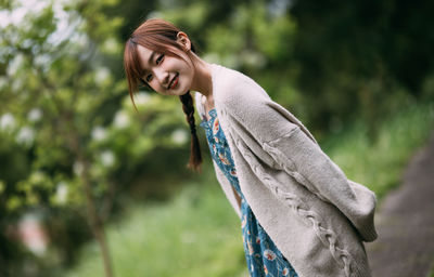 Young woman standing against trees