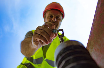 Low angle view of worker working screw against sky