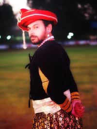 Side view of young man looking away while standing on field