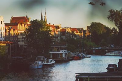 Buildings by river against sky in city