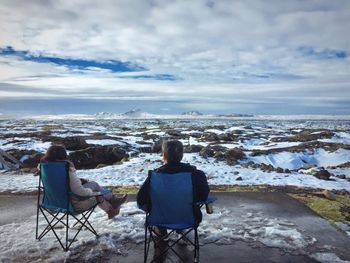 Rear view of people sitting on camping chair during winter