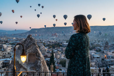 Woman looking at city buildings against sky