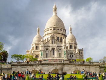 Group of people in temple against cloudy sky