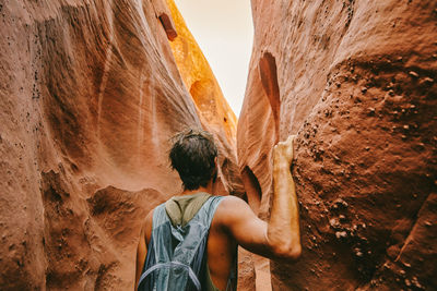 Young man exploring narrow slot canyons in escalante, during summer