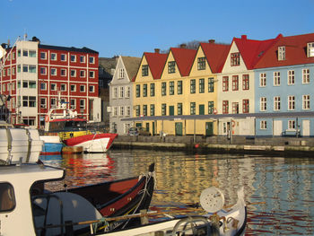 Sailboats moored on canal by buildings against sky in city