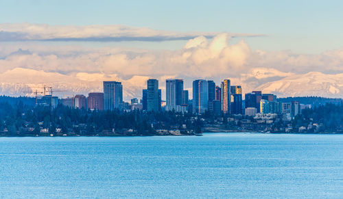 Sea by buildings against sky in city