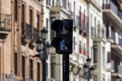 Low angle view of arrow sign on street against buildings