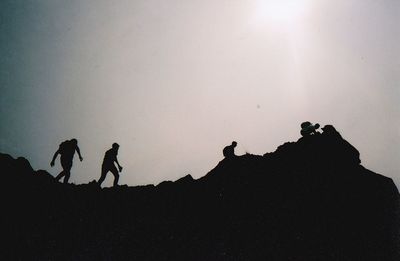 Silhouette people walking on land against sky