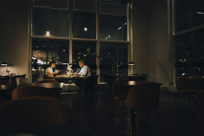 Male and female entrepreneurs working late in dark office at night