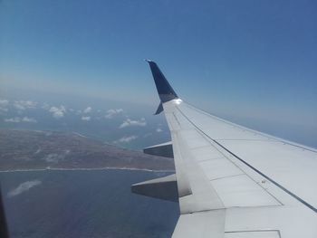 Airplane flying over mountain against blue sky