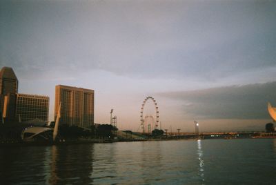 Scenic view of river by city buildings against sky