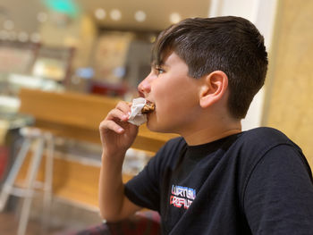 Boy eating a chocolate cookie with a napkin to avoid staining.