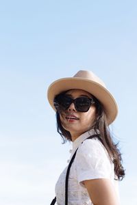 Portrait of woman wearing sunglasses standing against clear sky