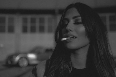 Close-up of woman smoking cigarette at night