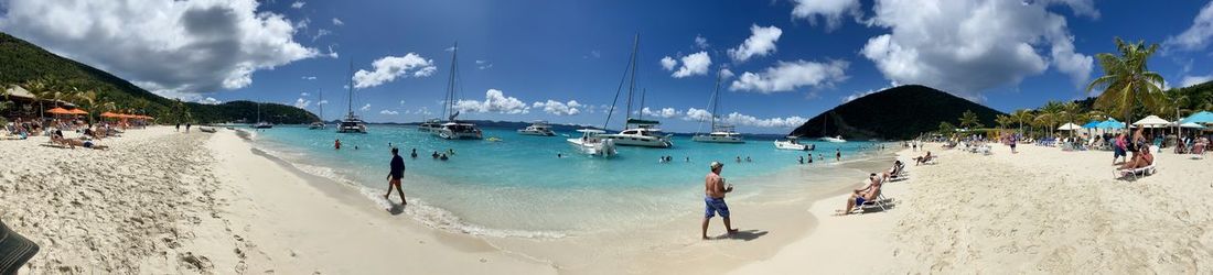Panoramic view of people on beach against sky