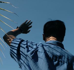 Rear view of man standing against clear blue sky