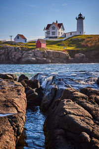 Lighthouse by sea against sky