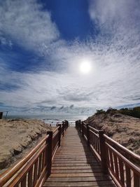 Boardwalk on pier over sea against sky