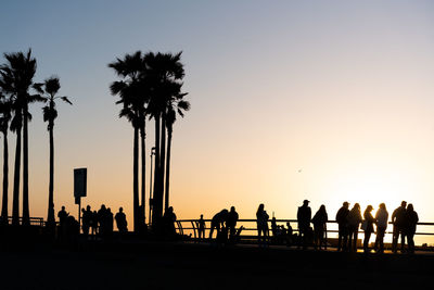 Silhouette people at beach against clear sky during sunset