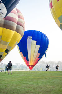 Photographers photographing hot air balloons against clear sky