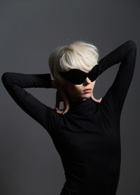 Rear view of woman with arms crossed against black background