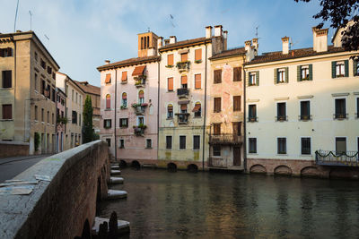 Canal amidst buildings in city against sky