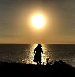 Silhouette man walking on beach against sky during sunset