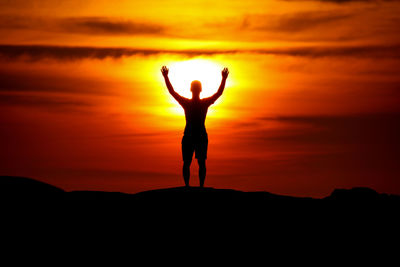 Silhouette man standing against orange sky