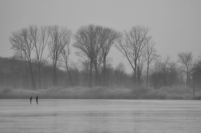 Distant view of friends standing on snow covered field