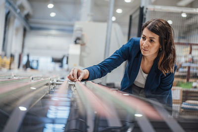Businesswoman analyzing machinery in workshop