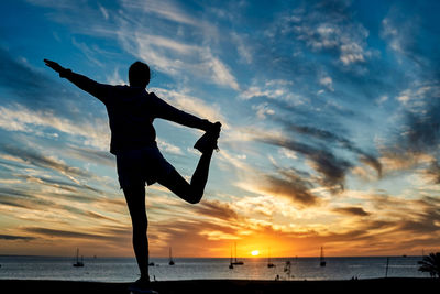 Silhouette man standing on beach against sky during sunset