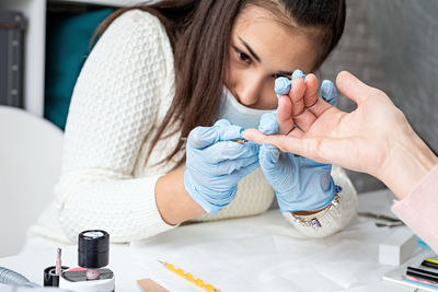 Young woman wearing glove and mask working at salon