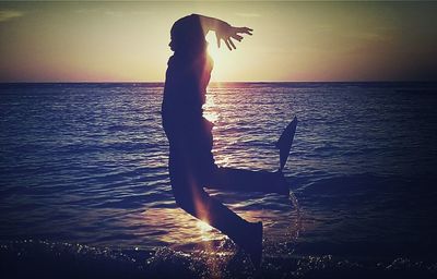 Silhouette person on beach against sky during sunset