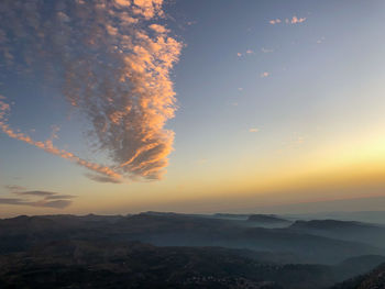 Scenic view of landscape against dramatic sky during sunset