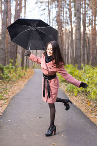 Full length portrait of woman standing on road