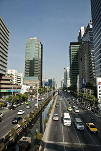 Vehicles on road in city against sky