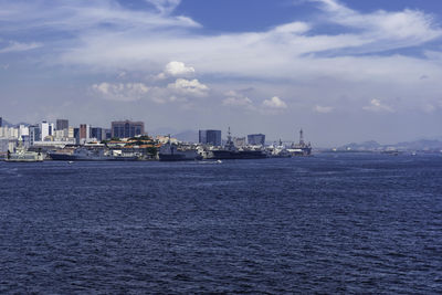 Sea by buildings in city against sky