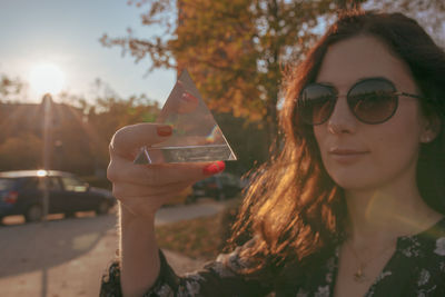 Close-up portrait of woman holding crystal in city during sunset