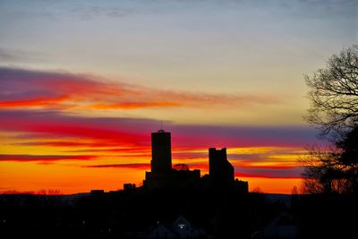 Silhouette of buildings against cloudy sky during sunset