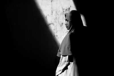 Side view of woman standing against wall