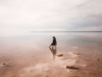 Woman sitting on bench at beach