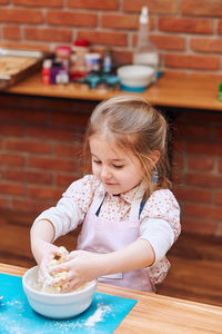 Girl kneading dough at kitchen counter