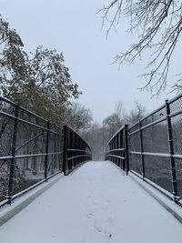 Snow covered footbridge against sky