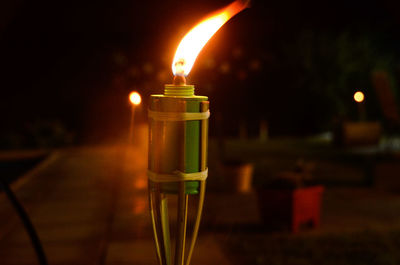 Close-up of illuminated candles on glass table