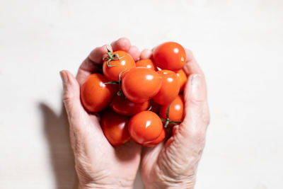 Cherry tomatoes in elderly woman's hans on white background
