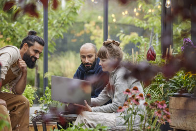 Smiling friends sitting in greenhouse