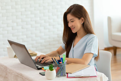 Young woman using laptop while sitting on table