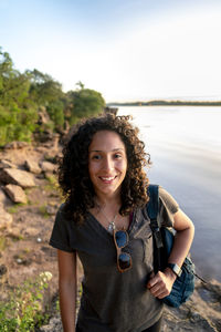 Portrait of young woman standing against lake