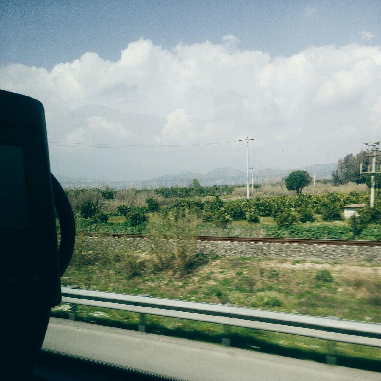 sky, transportation, road, cloud - sky, tree, cloud, land vehicle, car, mode of transport, nature, transparent, vehicle interior, day, landscape, cloudy, glass - material, mountain, growth, railroad track, street